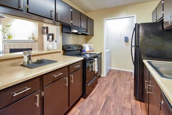 a kitchen with black cabinets and a wood floor  at Riverset Apartments, Memphis